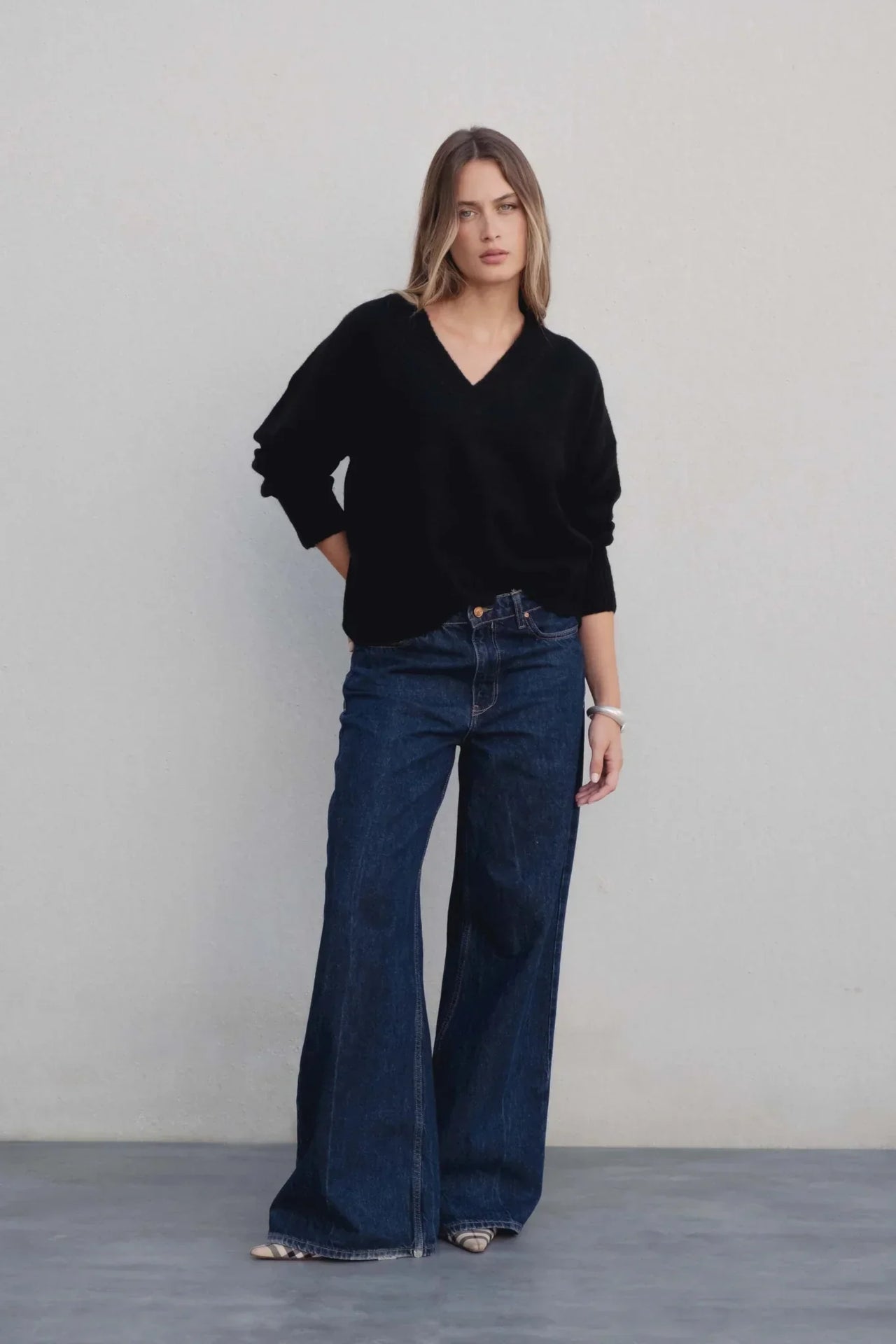 Modèle stylé avec un pull oversize noir col V associé à un jean large, parfait pour une tenue casual chic avec pull laine femme.