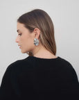 Profil d'une femme portant un pull oversize noir col V, accent sur des boucles d'oreilles, parfait pour compléter un look avec pull laine femme.