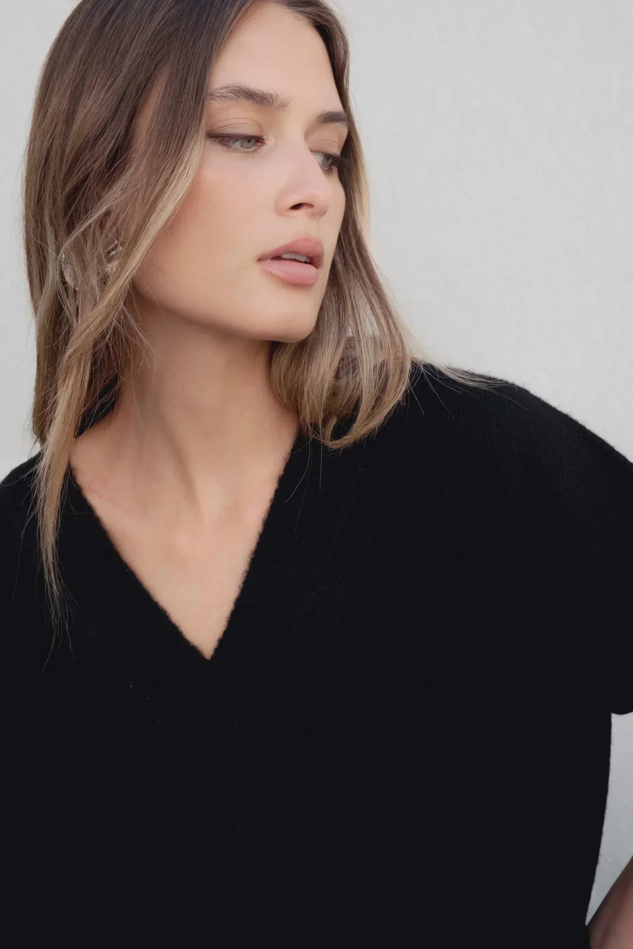 Femme présentant un pull oversize noir col V, un style moderne et décontracté, idéal dans une garde-robe de pull laine femme.