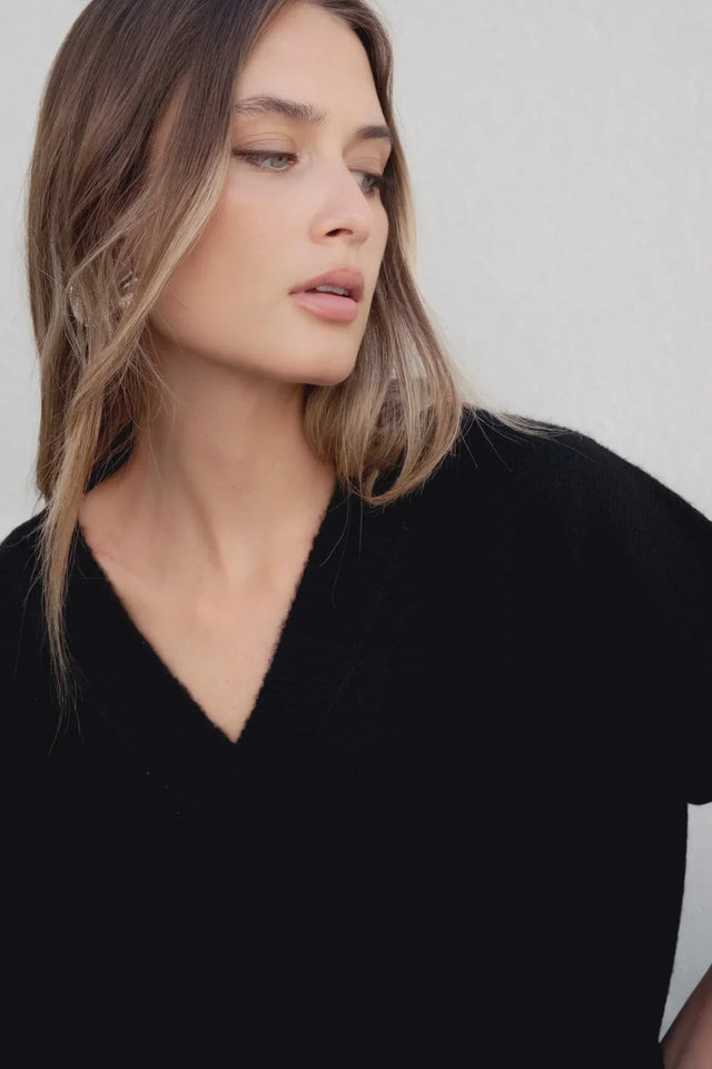 Femme présentant un pull oversize noir col V, un style moderne et décontracté, idéal dans une garde-robe de pull laine femme.