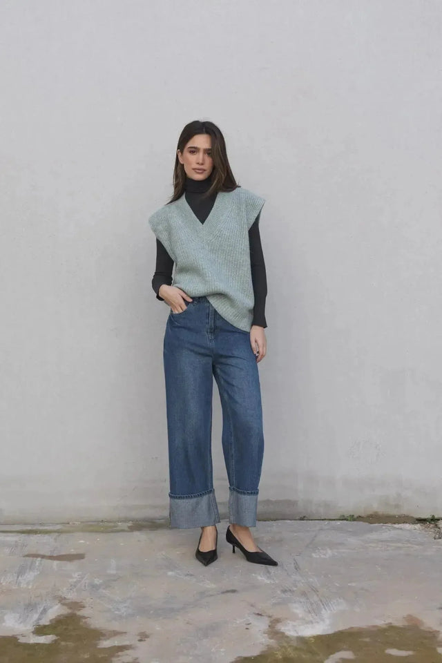 Femme avec un pull sans manche femme oversize en tricot col V doux associé à un jean, créant un look automnal sophistiqué.