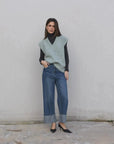 Femme avec un pull sans manche femme oversize en tricot col V doux associé à un jean, créant un look automnal sophistiqué.
