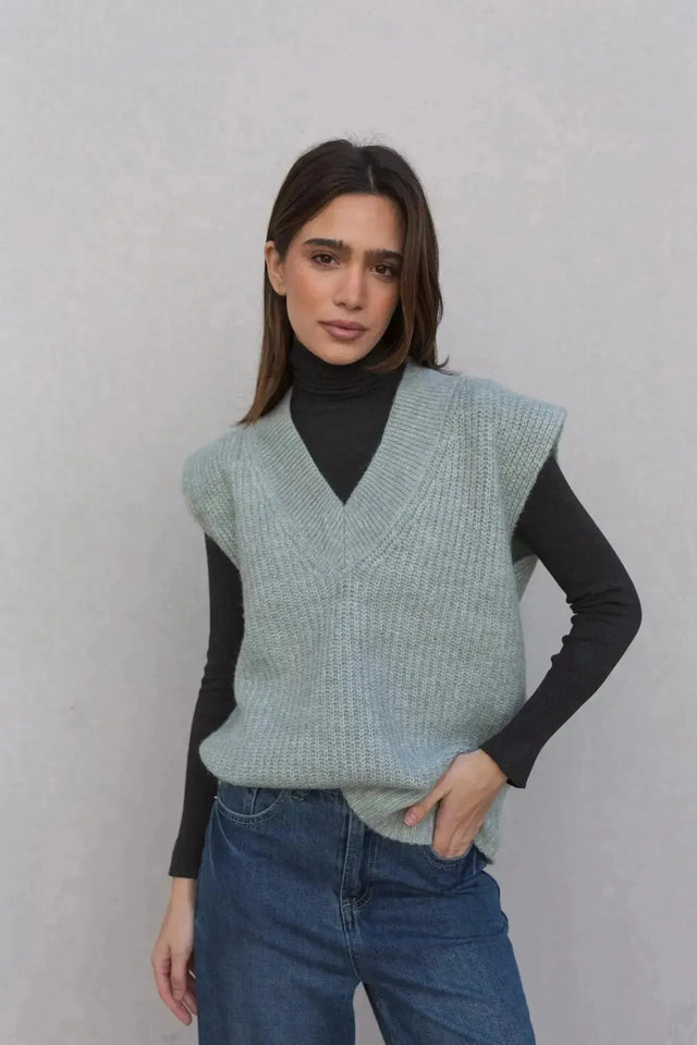 Femme posant avec un pull sans manche femme oversize en tricot col V doux, offrant un look moderne et stylé.