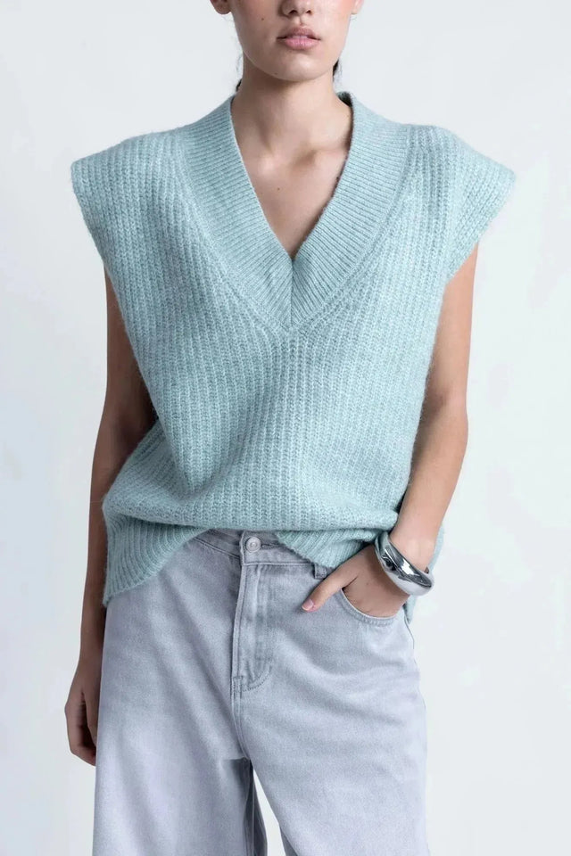 Gros plan sur un pull sans manche femme oversize en tricot col V doux, stylé avec un jean, parfait pour une tenue chic.