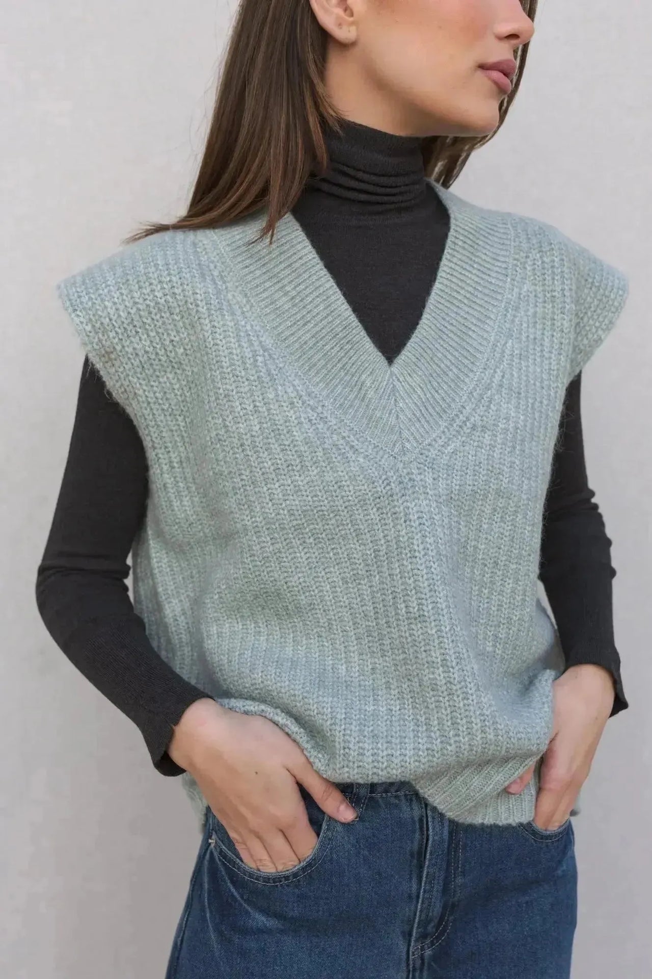 Femme élégante portant un pull sans manche femme oversize en tricot col V doux sur un col roulé, soulignant le confort et le style.