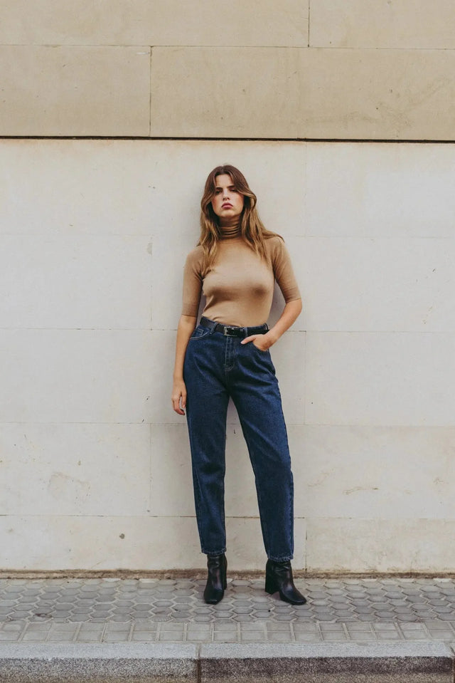 Pull col roulé femme beige tricoté, confortable et chic pour automne-hiver, avec une femme posant dans un cadre urbain.