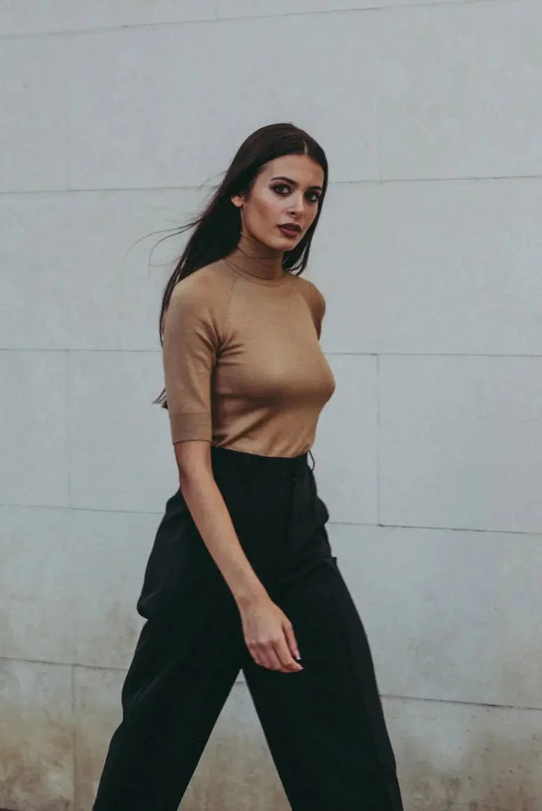 Pull col roulé femme beige tricoté, confortable et chic pour automne-hiver, femme marchant élégamment dans un style urbain.