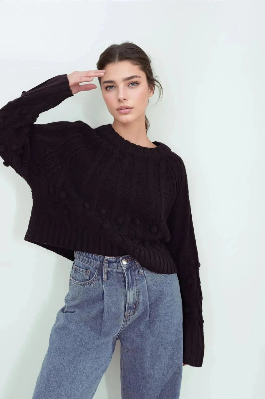 Femme posant avec le pull laine femme noir à torsades, mettant en avant son originalité avec des motifs, confort élevé pour l'hiver.