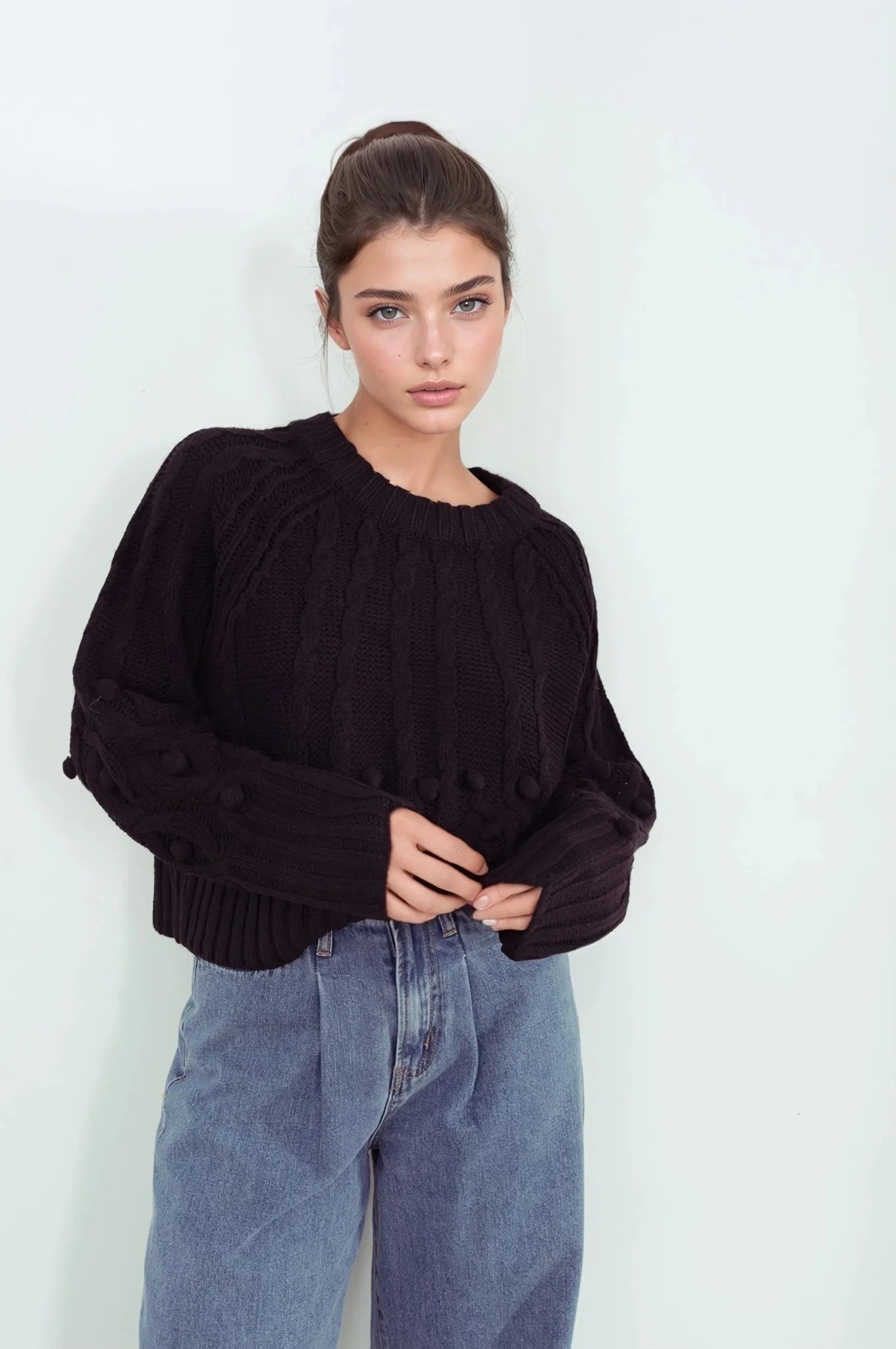 Femme portant un pull tricoté noir et jeans larges plissés pull tricoté
