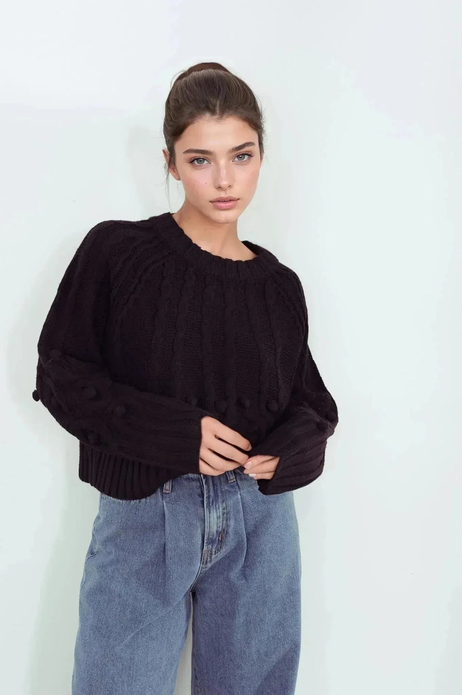 Modèle portant le pull laine femme noir à torsades, style décontracté avec un jean, confort et élégance pour l'hiver.