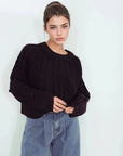 Modèle portant le pull laine femme noir à torsades, style décontracté avec un jean, confort et élégance pour l'hiver.
