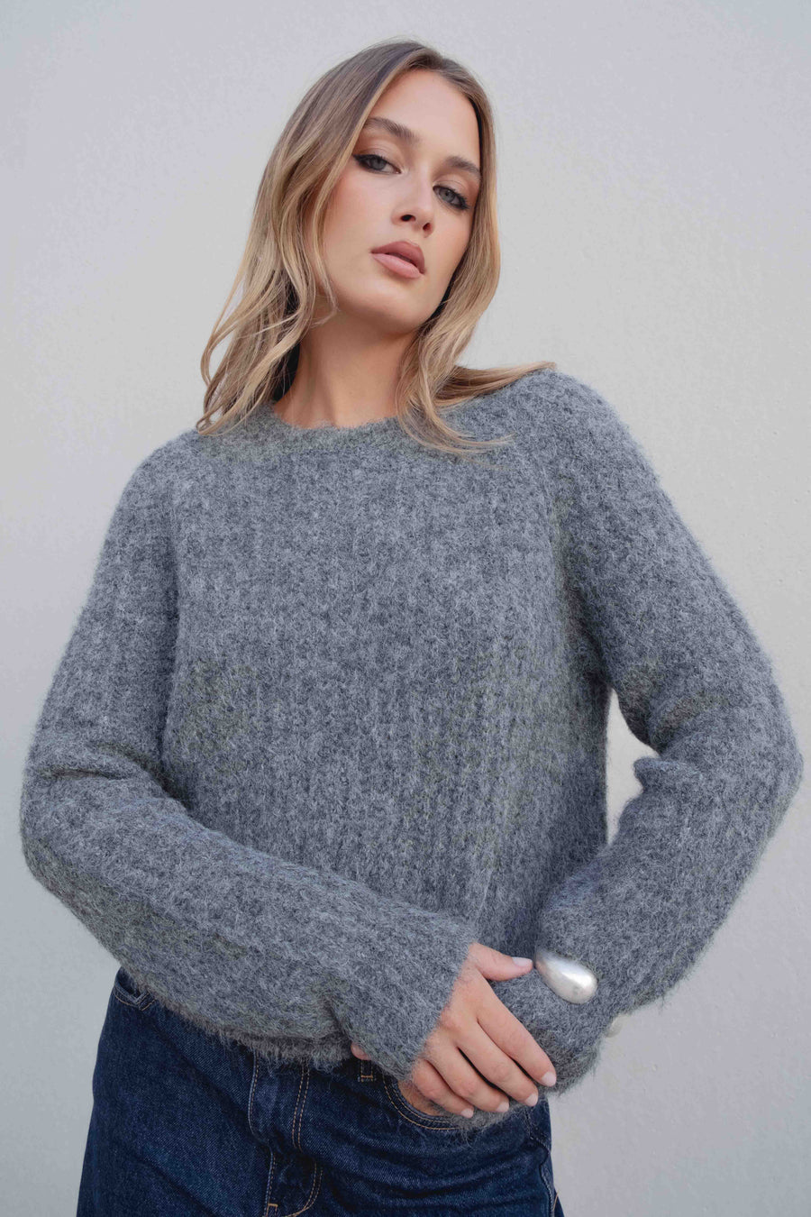 Détail du pull maille oversize gris, mettant en valeur la texture côtelée et la silhouette confortable.