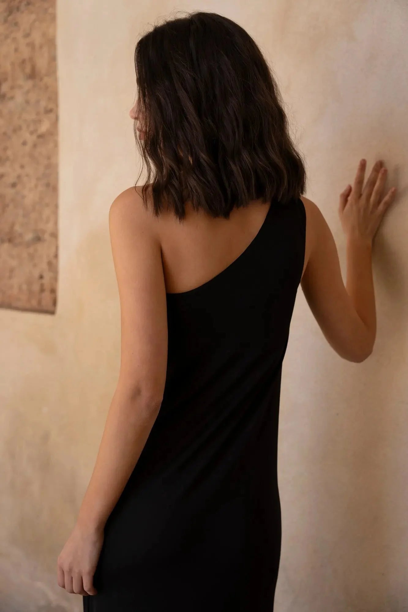 Femme en robe asymétrique bijou noire, idéal pour occasions spéciales