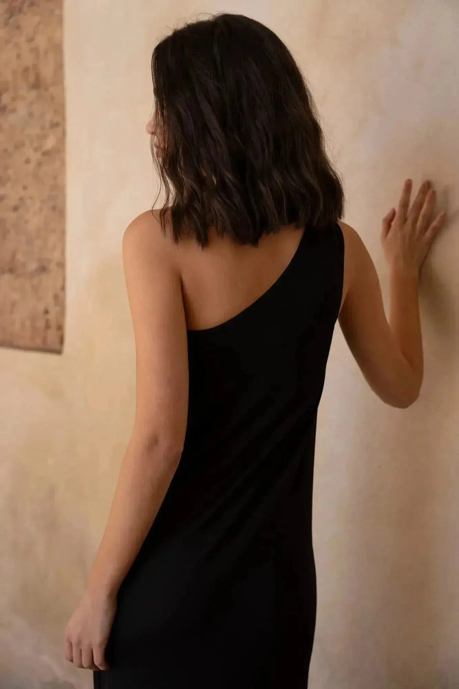 Femme en robe asymétrique bijou noire, idéal pour occasions spéciales