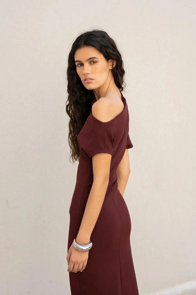 Femme tournant avec une robe asymétrique chic bordeaux – Coupe élégante et polyvalente en polyester, alliant confort et style.
