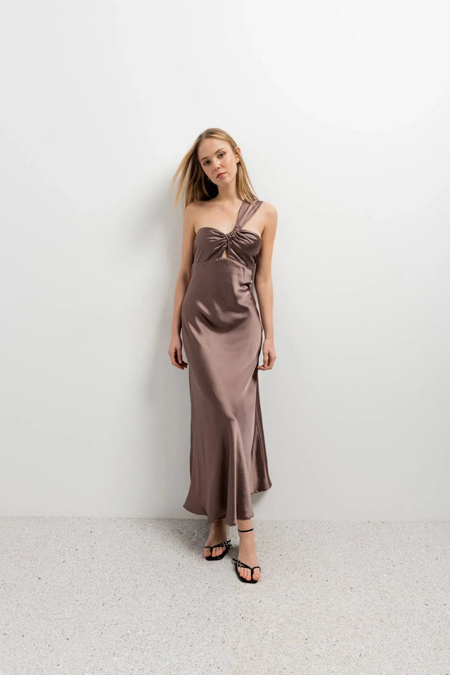 Femme posant fièrement dans une robe de soirée femme asymétrique chic en satin marron, pour un look tendance.