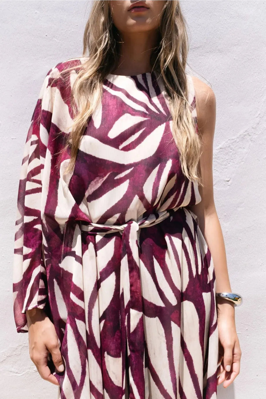 Détail de la robe asymétrique imprimée, conforme au style robe hippie année 70, montrant les motifs artistiques bordeaux.