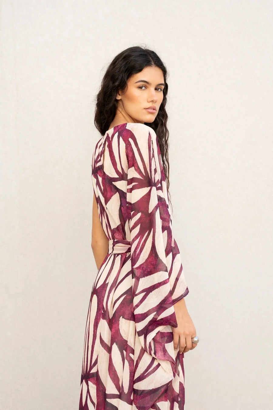 Femme regardant au loin dans une robe asymétrique imprimée, reflétant le style robe hippie année 70, avec des motifs et une silhouette unique.