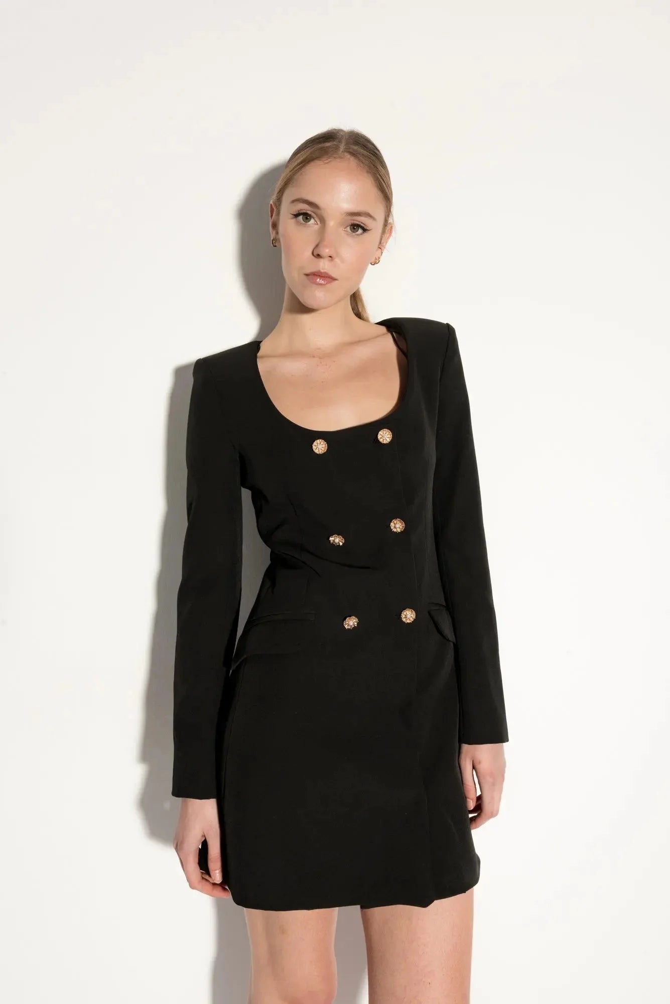 Femme portant une robe blazer noire avec boutons dorés, élégance et style structuré