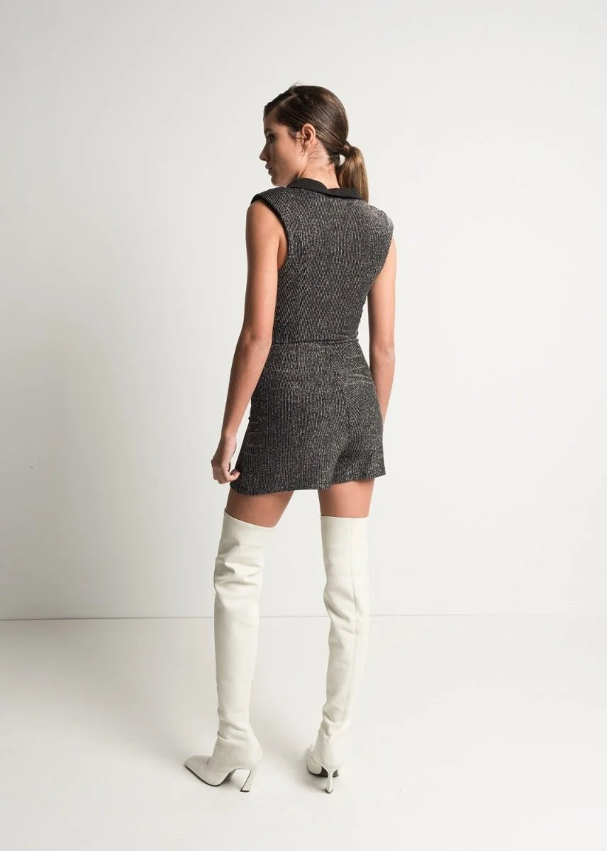 Femme portant une robe blazer scintillante sans manches et des bottes hautes blanches