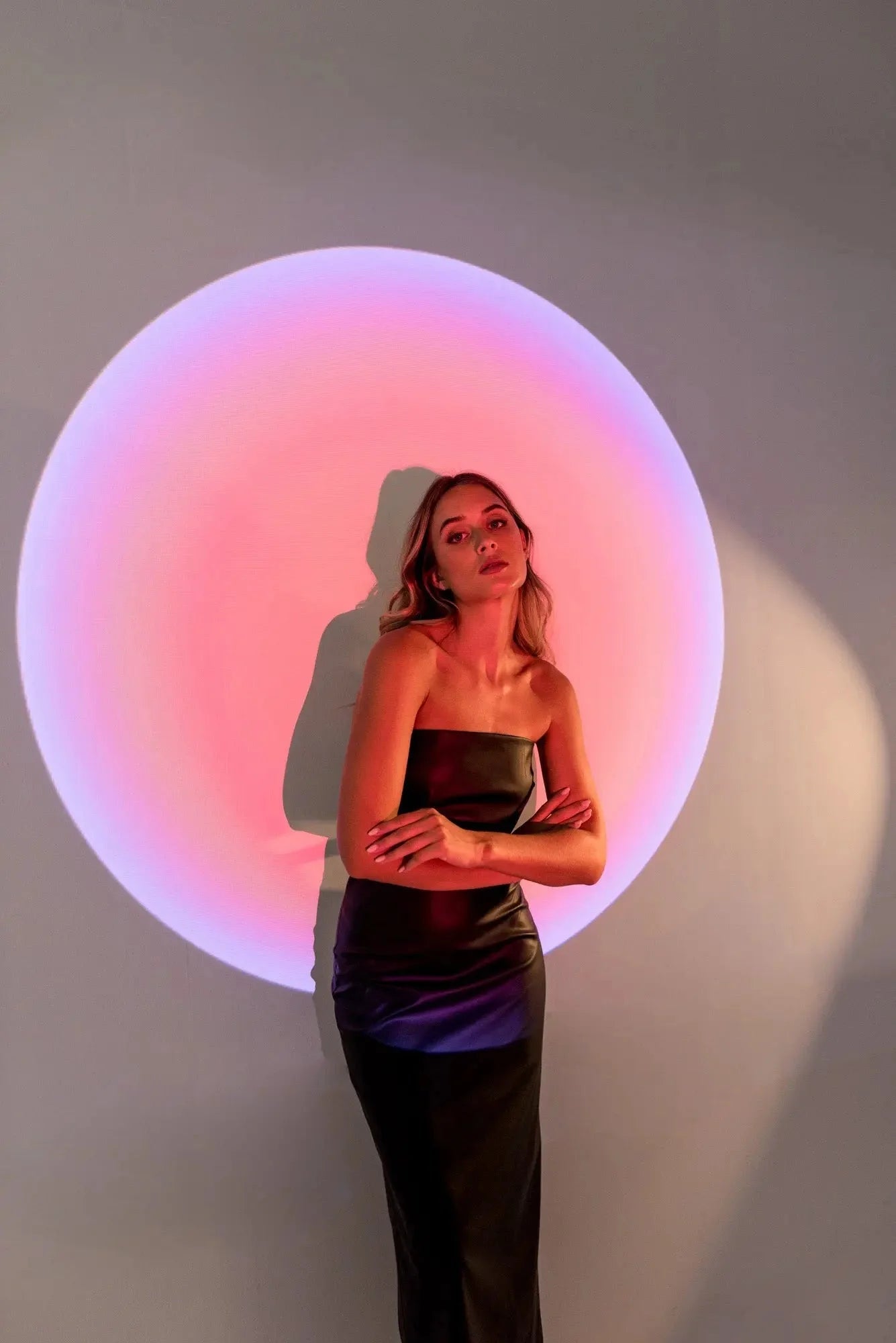 Femme en robe bustier noire effet cuir avec grand affichage lumineux en arrière-plan