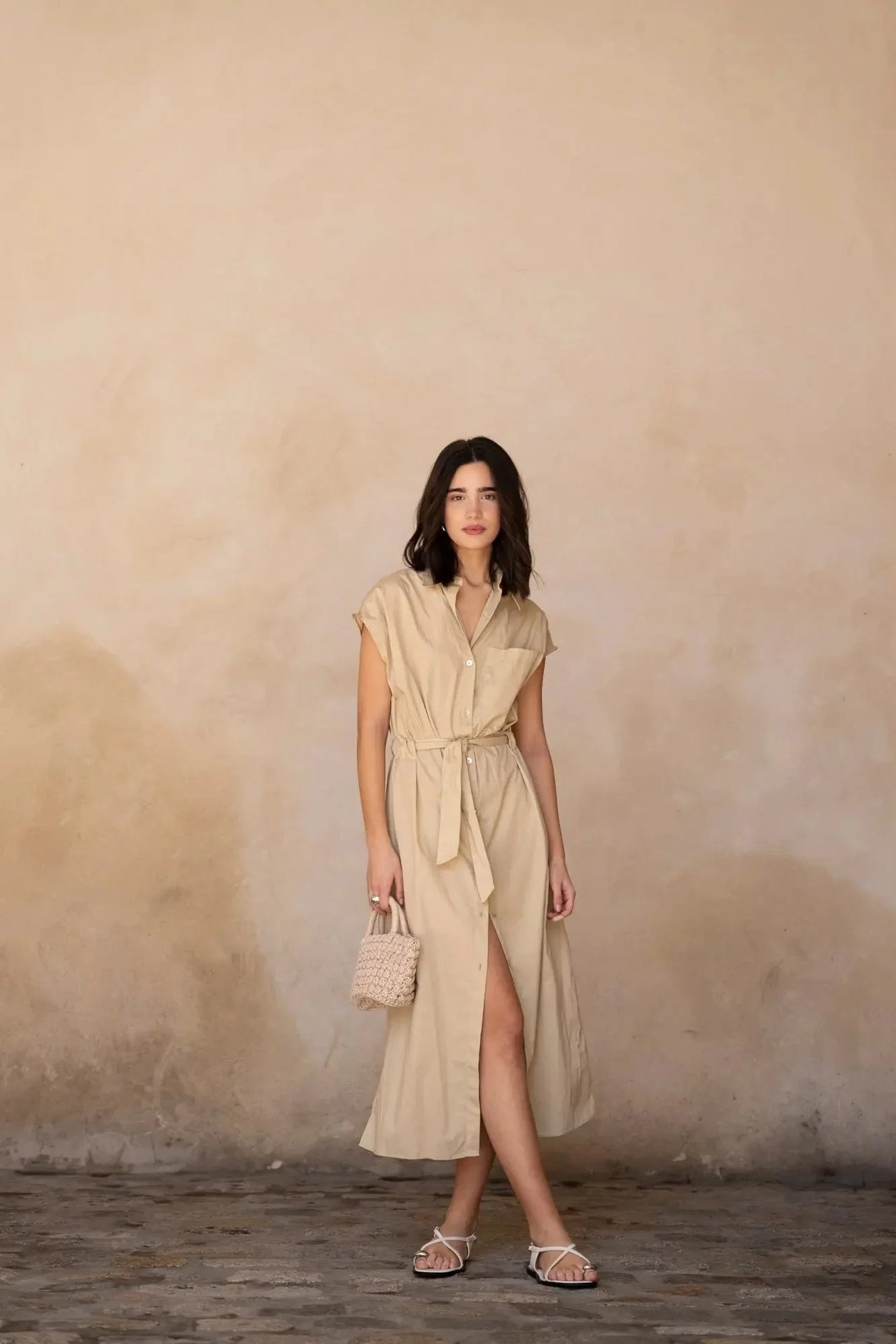 Femme marchant en robe chemise femme beige midi ceinturée, affichant une allure élégante et décontractée avec un sac tendance.