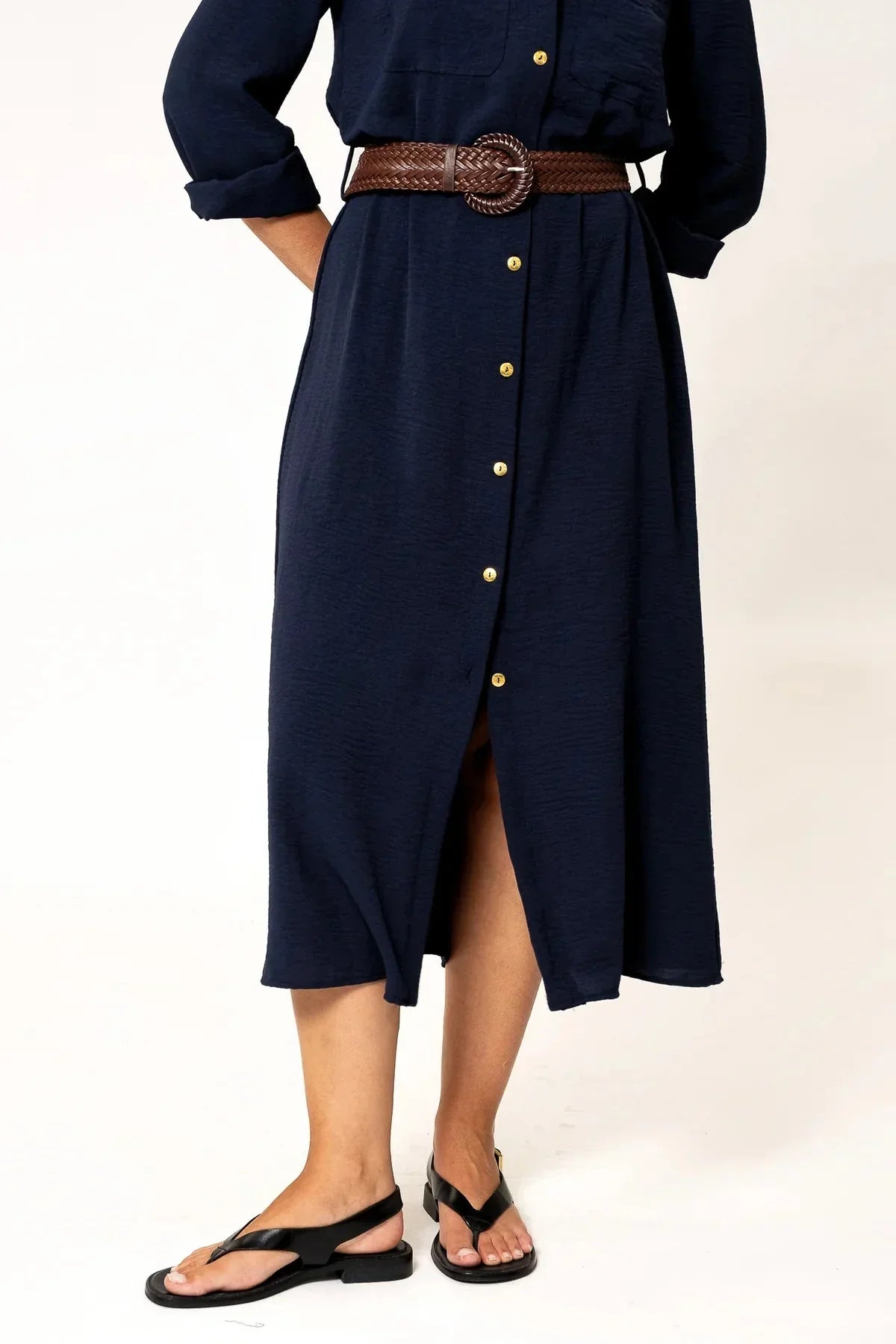 Focus sur le bas de la robe chemise longue bleu marine avec fente, sur une mannequin, ajoutant une touche moderne et décontractée.