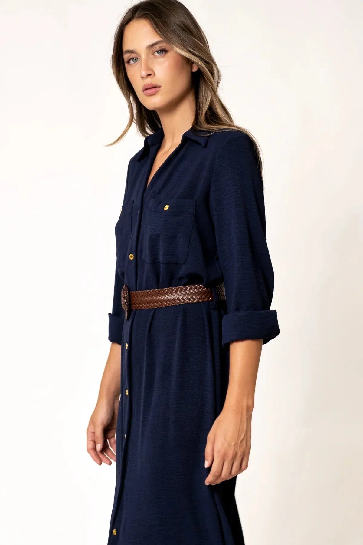 Détail de la robe chemise longue bleu marine avec boutons dorés, mise en valeur par une ceinture tressée, parfaite pour un look chic.