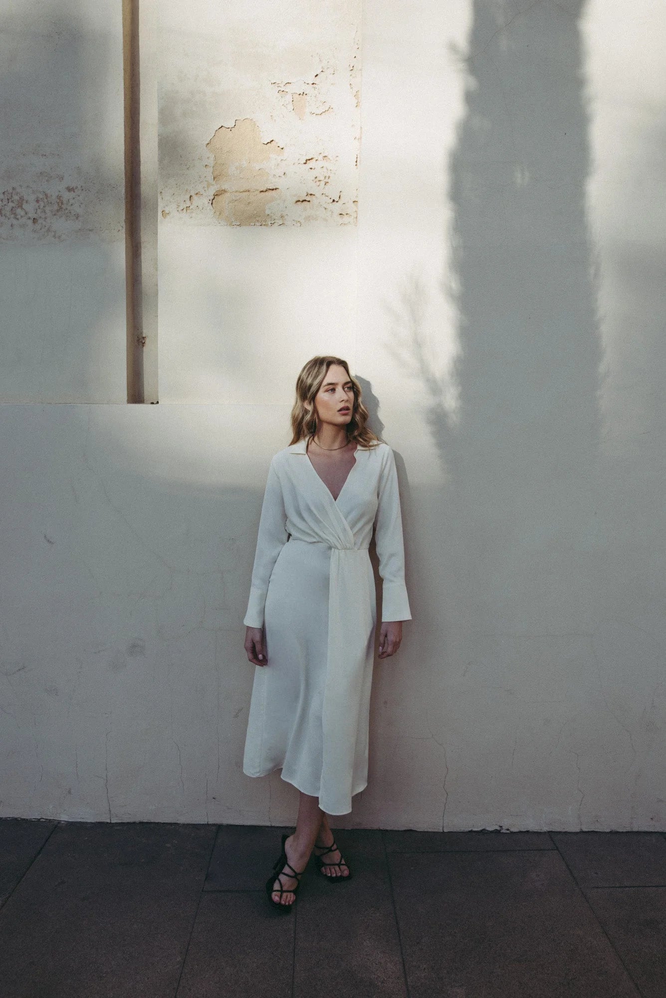 Robe chemise en satin blanche portée par une femme avec sandales noires à brides