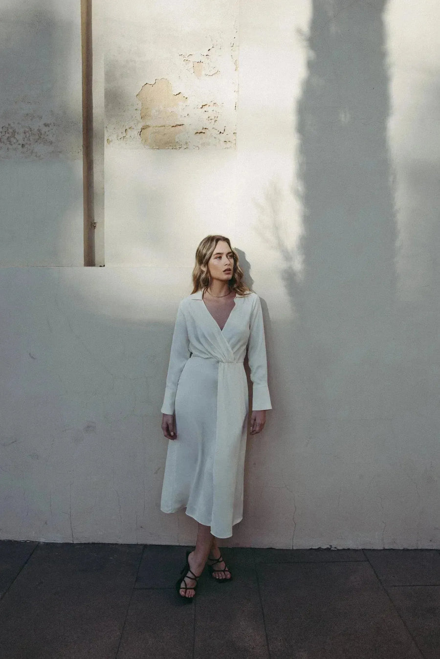 Robe chemise en satin blanche portée par une femme avec sandales noires à brides