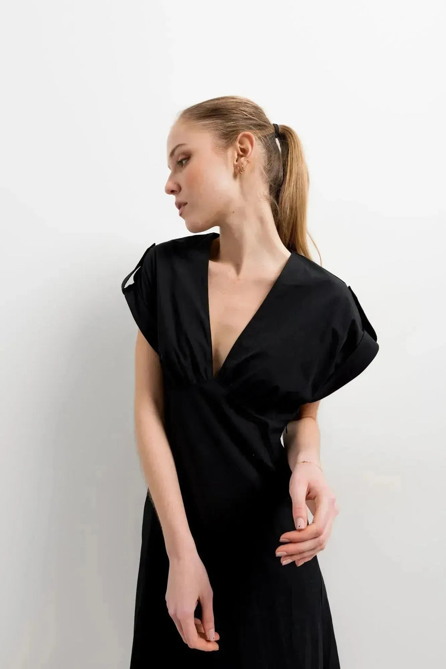 Détail du décolleté en V de la robe popeline noire chic à manches courtes - évasée pour toutes occasions, avec un modèle observant.