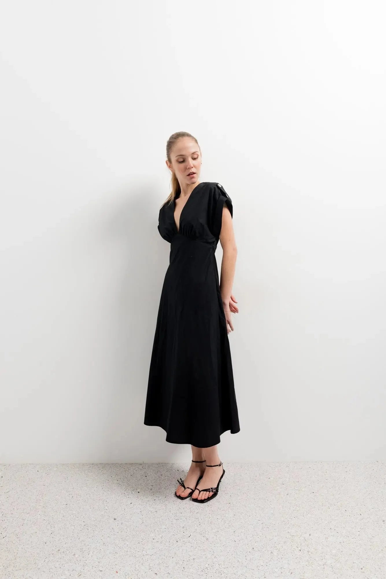 Modèle mettant en valeur une robe popeline noire chic à manches courtes - décolleté en V évasée pour toutes occasions, sur fond blanc.