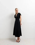 Modèle mettant en valeur une robe popeline noire chic à manches courtes - décolleté en V évasée pour toutes occasions, sur fond blanc.