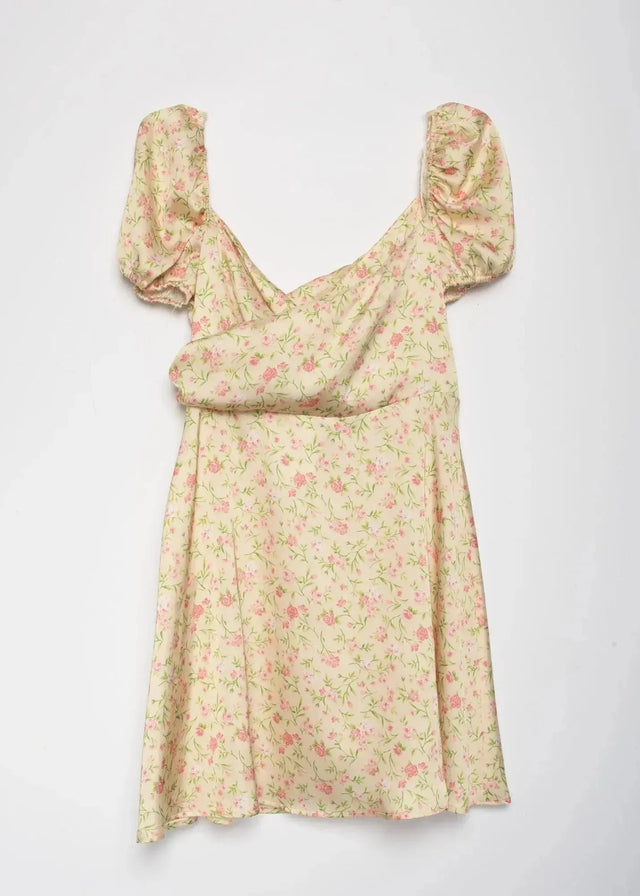 Mini Robe Florale Romantique Jaune Pâle Avec Décolleté Cache-Cœur Et Manches Bouffantes présentée sur fond blanc.