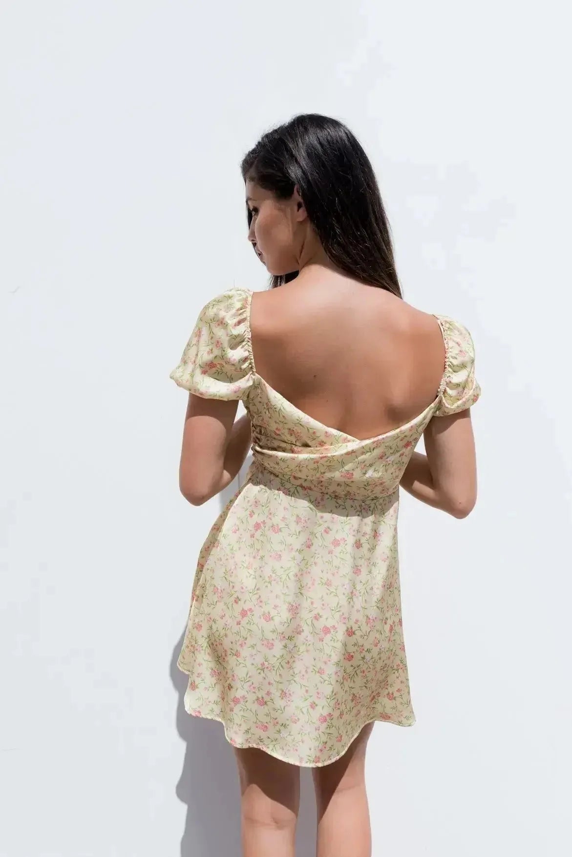 Vue arrière d'une Mini Robe Florale Romantique Jaune Pâle Avec Décolleté Cache-Cœur Et Manches Bouffantes, montrant le design élégant du dos.