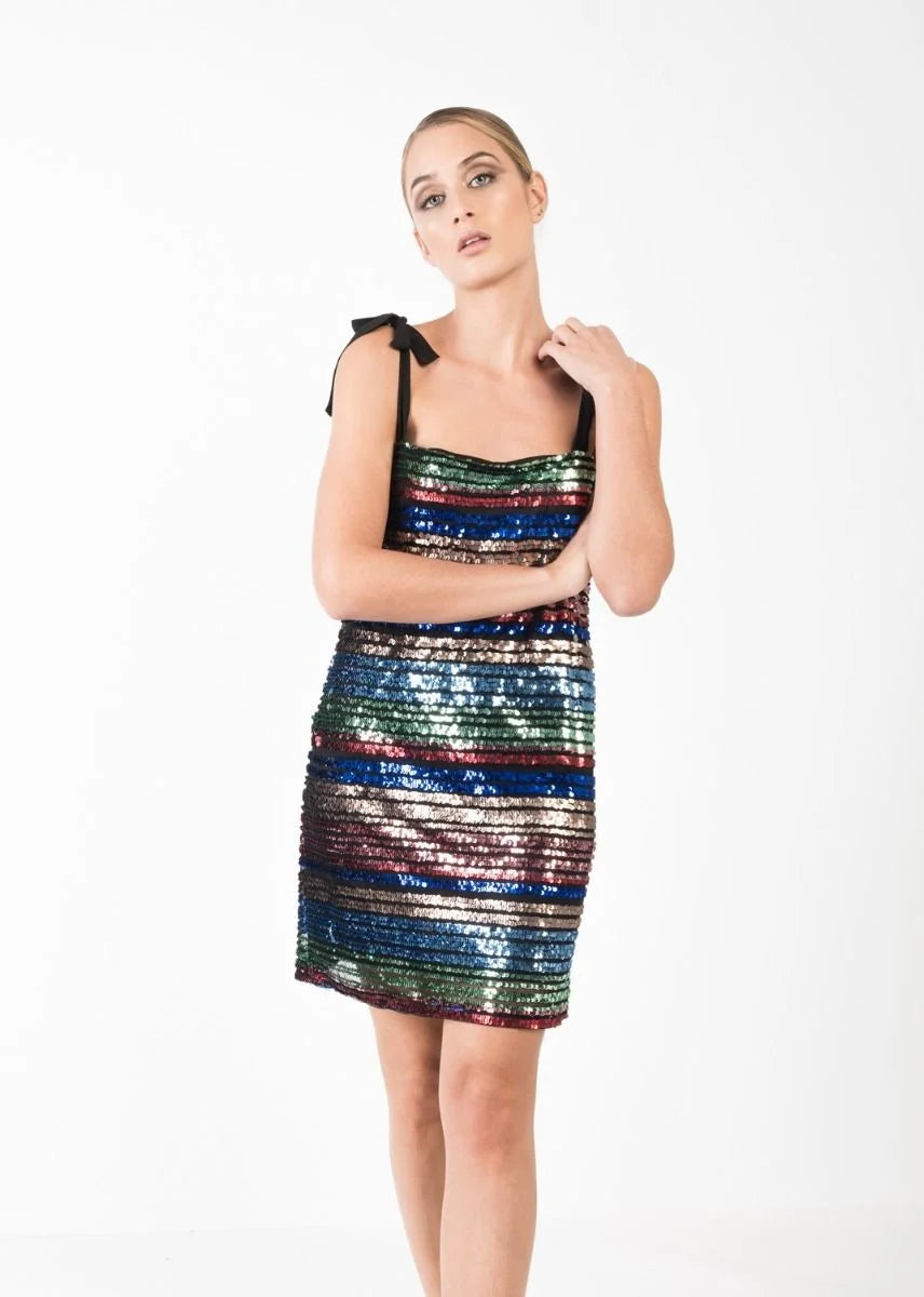 Femme en pose avec une robe courte à paillettes multicolores, élégante et chic pour soirées festives, affichant un design moderne.