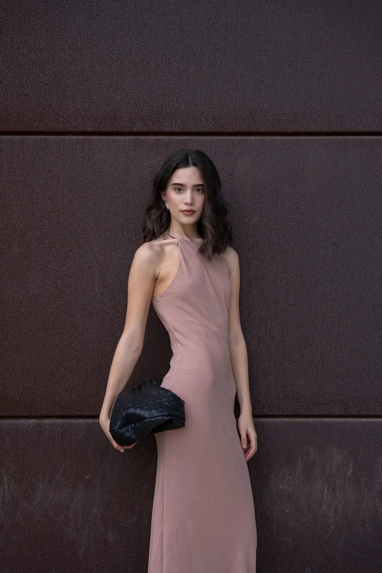 Femme en robe halter élégante et intemporelle, portant un sac à main noir