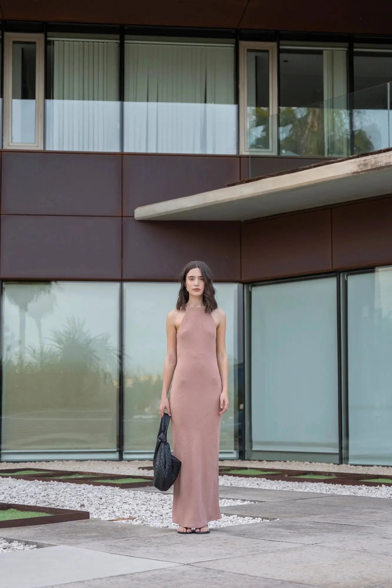 Femme en robe halter élégante mauve longue avec sac noir, style intemporel
