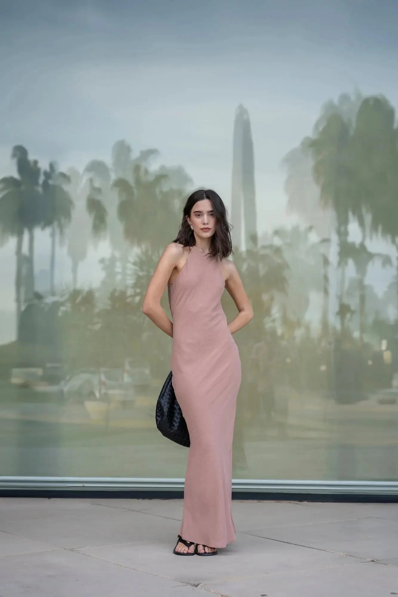 Femme portant une robe halter élégante en rose poussière et sandales noires
