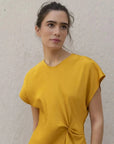 Robe De Soirée Jaune Satinée Élégante Avec Nœud À La Taille - Chic Et Fluide, gros plan sur un modèle féminin souriant en robe de soirée jaune satinée.