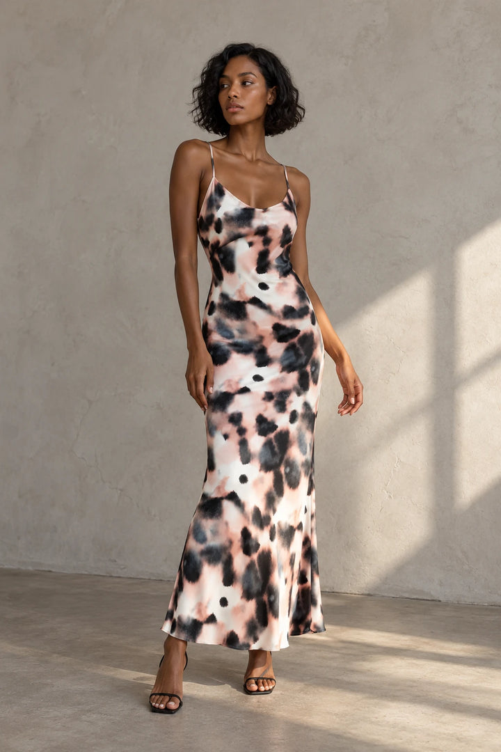 Modèle posant avec une robe longue à imprimé tie-dye, mettant en avant son motif unique et ses couleurs vives. Idéal pour le printemps et l'été, cette robe tie and dye est parfaite pour des occasions décontractées.