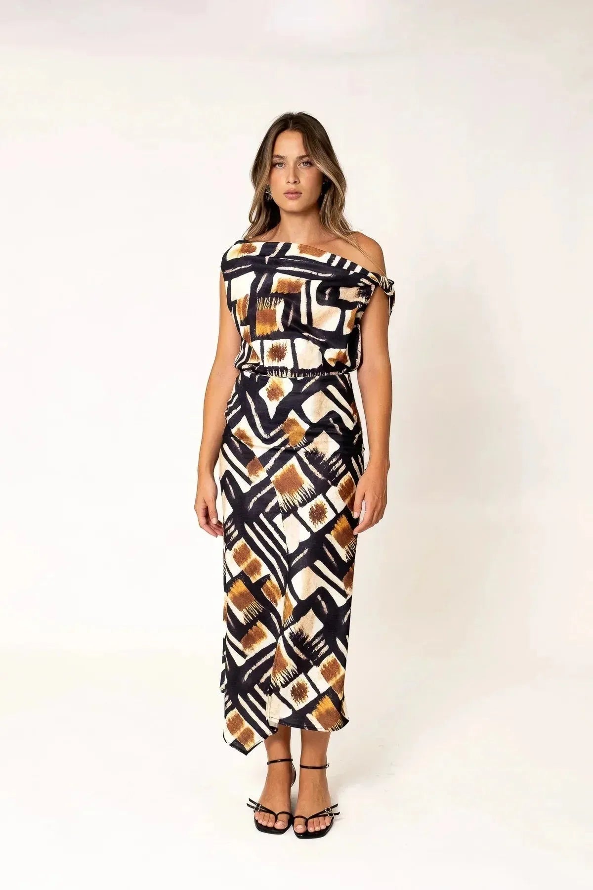 Femme en haut femme asymétrique à une épaule imprimé graphique marron, noir et blanc, avec une pose confiante, mettant en avant le caractère chic et moderne de la mode.