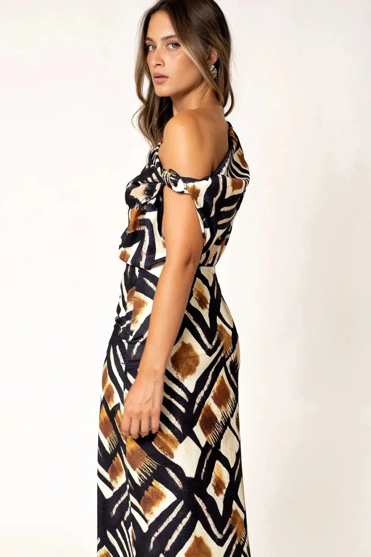 Profil d'une femme portant un haut femme asymétrique à une épaule imprimé graphique marron, noir et blanc, montrant le drapé du tissu et un style contemporain.