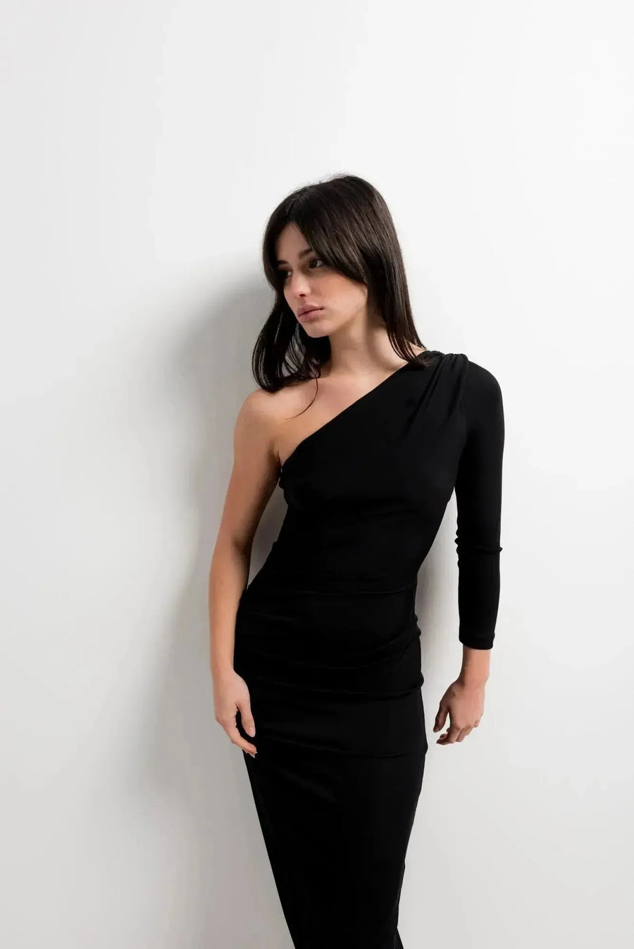 Détail sur la robe asymétrique une manche noire, avec son design chic affiché par le modèle.