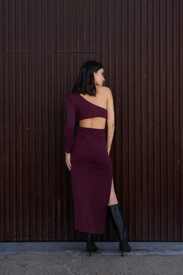 Vue arrière du modèle en robe asymétrique une manche bordeaux, montrant le design distinctif et élégant.