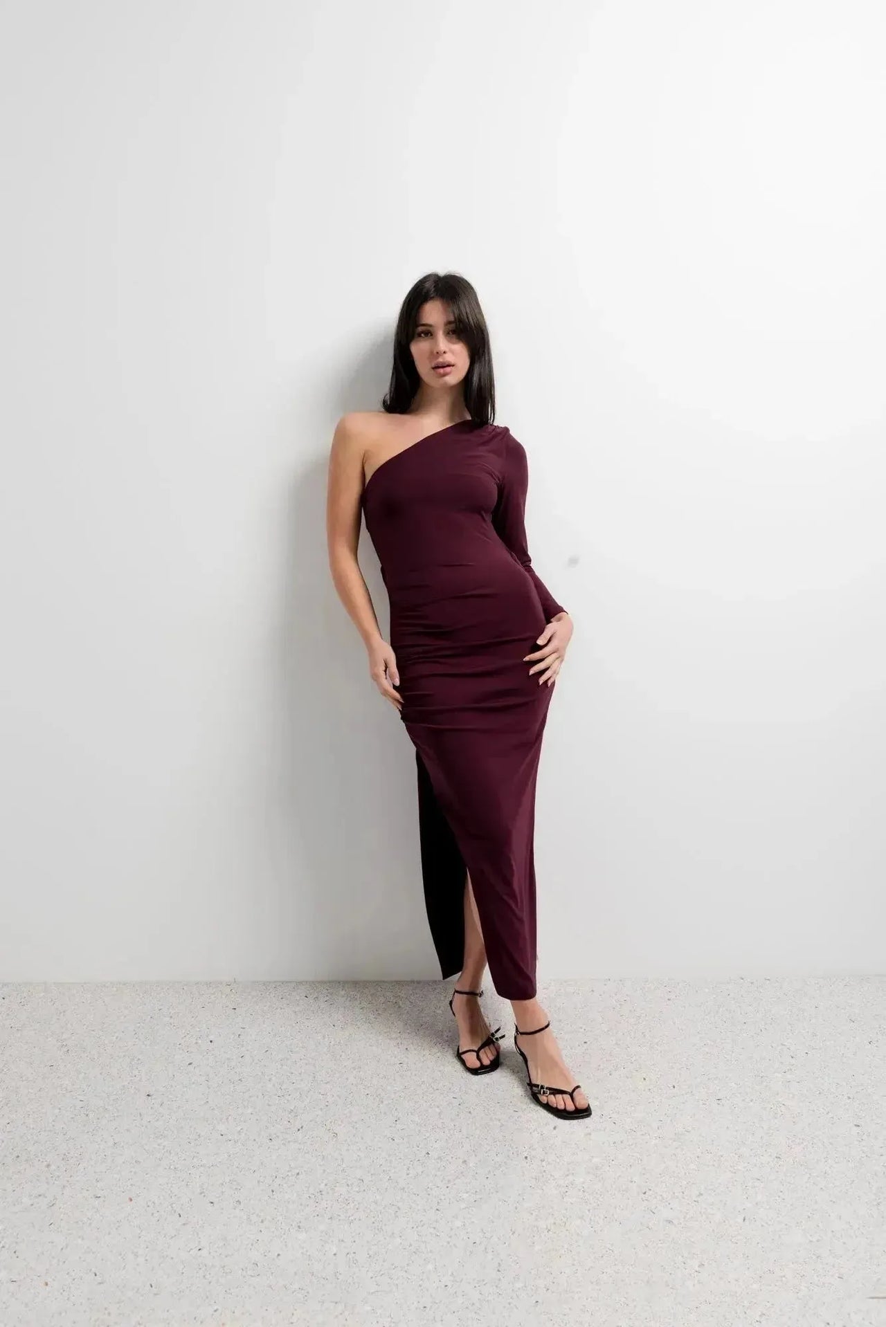 Modèle avec la robe asymétrique une manche bordeaux, affichant une allure chic et raffinée pour des occasions spéciales.