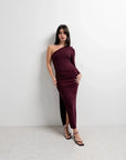 Modèle avec la robe asymétrique une manche bordeaux, affichant une allure chic et raffinée pour des occasions spéciales.