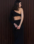 Vue de côté de la robe asymétrique une manche noire sur le modèle, montrant la coupe flatteuse et moderne.