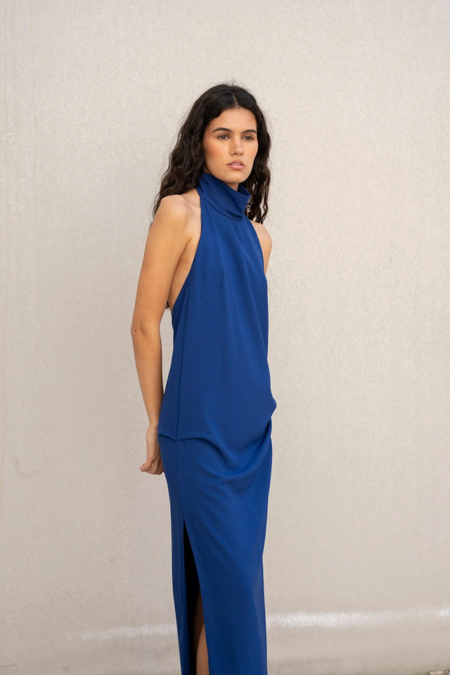 Femme regardant l'objectif en robe longue dos nu Sapiato, avec une coupe moderne, affichant un look sophistiqué.