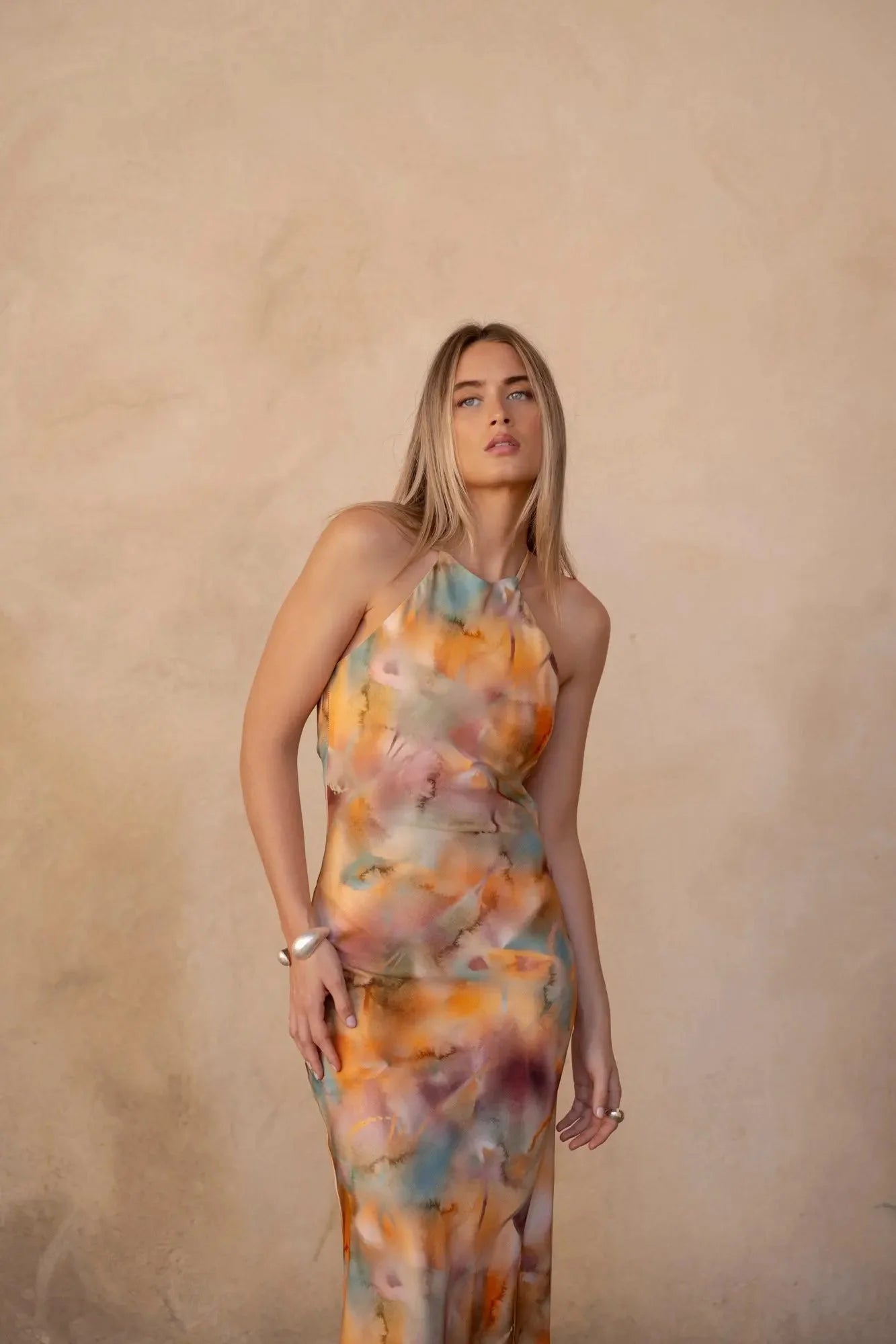 Modèle en plein pose avec la robe satin longue dos nu imprimée aquarelle multicolore – Élégance fluide et chic, expressive et stylée.